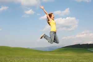 Woman jumping for joy in mountain meadow side view